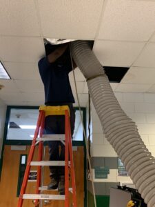 a professional from Air Quality Systems cleaning an air duct